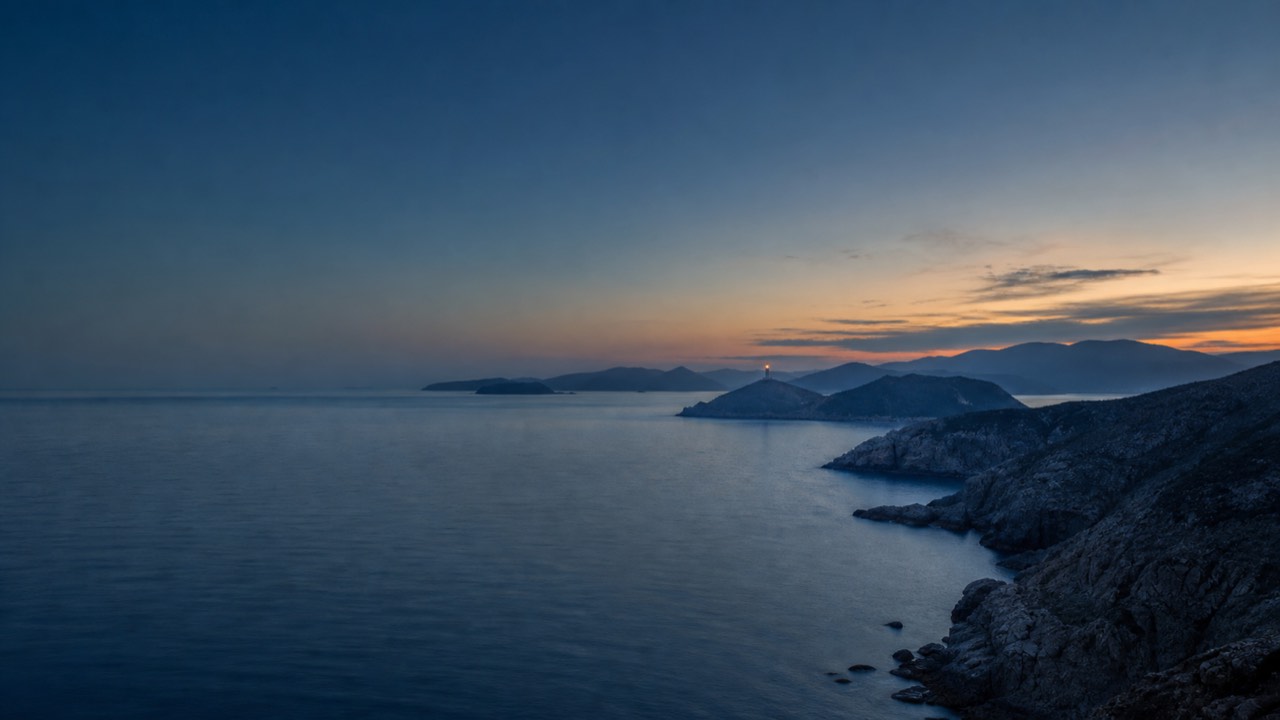 暮色中的海岸,远山与灯塔静静立在海面上